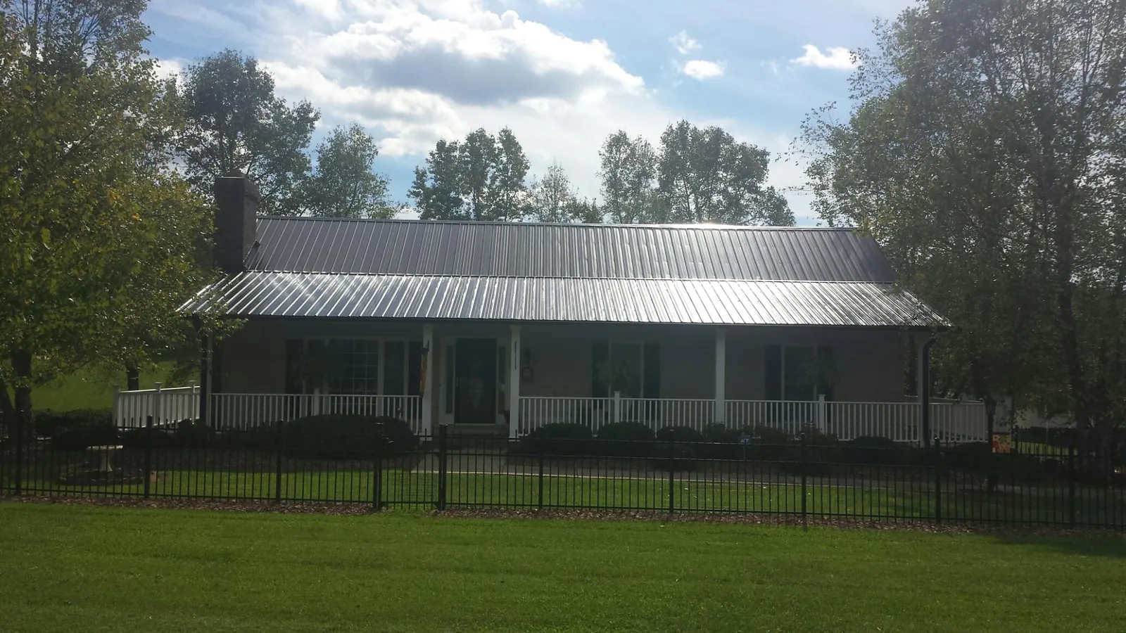 Gray metal roof on a brick ranch with a full width front porch — Gutter Guard Installation work by our crew in Bryant